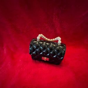 Black patent leather tufted evening bag with white pearl handle